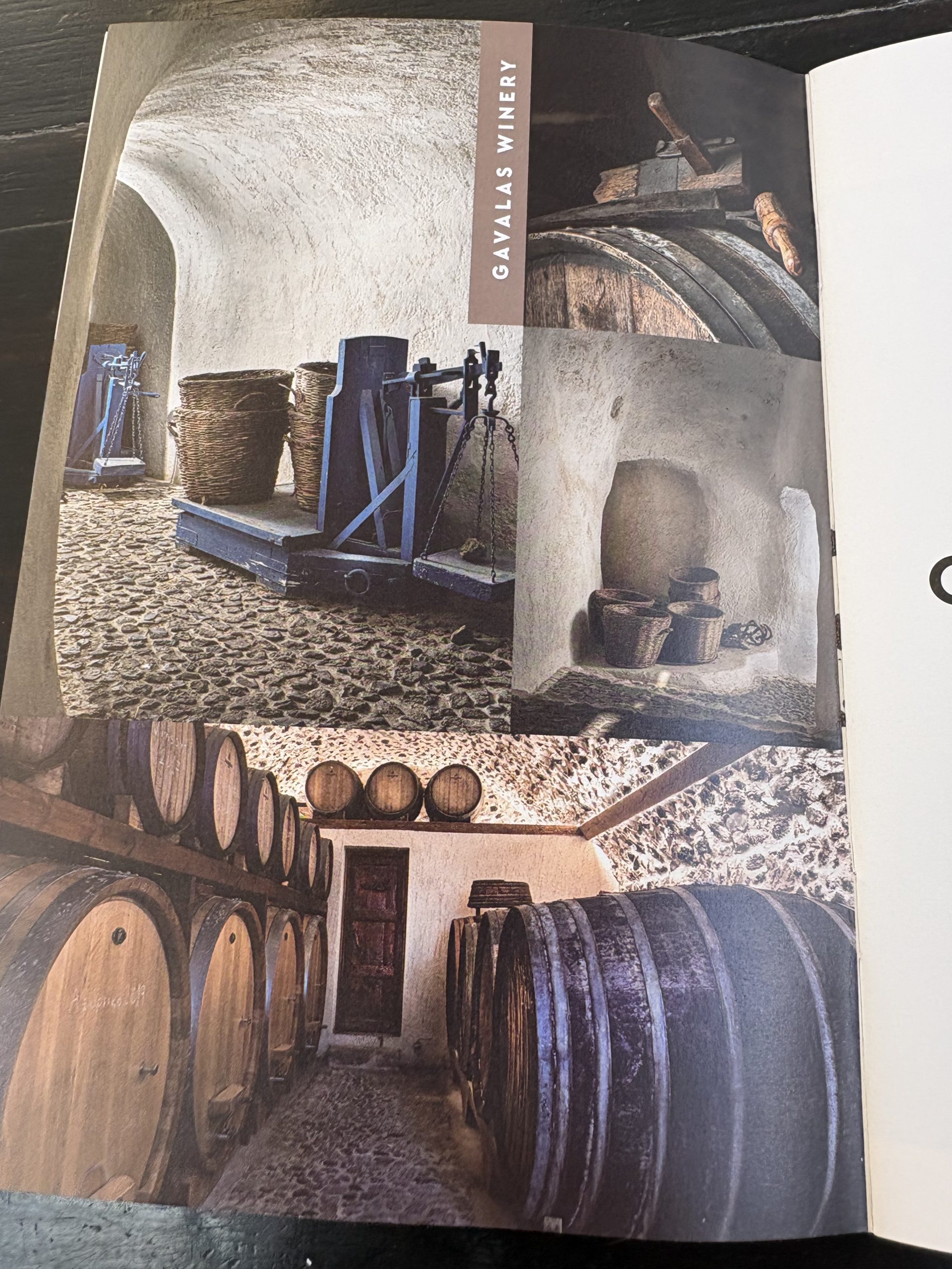 The centuries-old cave cellar at Gavalas Winery with oak barrels, traditional wine press, and volcanic stone architecture